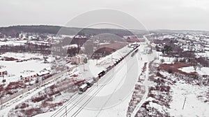 Railway road with freight trains, aerial drone shot. Small village with railway station