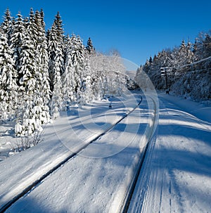 Railway through snowy fir forest and remote alpine helmet in Carpathian mountains, snow drifts  on wayside
