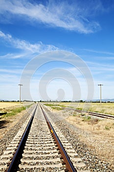 Railway station against beautiful sky at sunset. Industrial landscape with railroad, colorful blue sky with red clouds, sun, trees