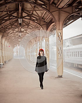 Railway station. Beautiful woman goes from train looking at camera. Female travels light. Middle-aged lady