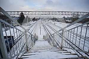 Railway station with a bridge and a train with wagons in winter