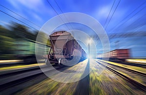 Railway station with cargo wagons and train light in motion