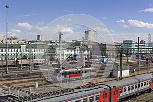 Railway station with a many rail tracks and modern trains and cars on the background of the city, aerial view