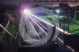 Railway station at night with a passing train