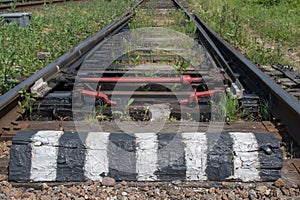 Railway switchboard with electric drive and red rod fixed on resinous sleepers, with chipping bar in black and white stripes.