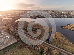 Railway to Galway city, Aerial drone view. Warm sunset sky and glow over town buildings