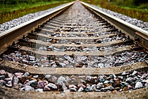 Railway track line going into distance, railroad train track with crushed stone, two parallel rails