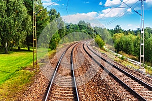 Railway tracks with catenary and summer landscape