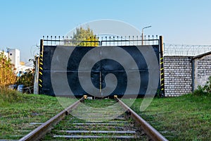 Railway tracks run into the black gate of the industrial zone