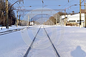 The railway tracks stretching into the distance are covered with snow