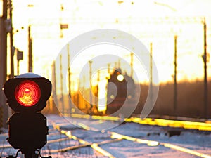 Railway traffic light shows blue signal on railway and railway with freight train as the background