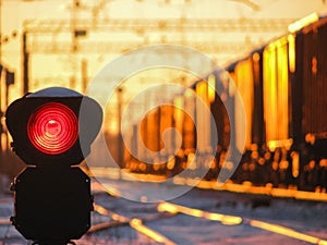 Railway traffic light at sunset shows red signal on railway