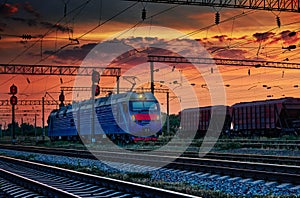 Railway train and rail cars in a beautiful sunset, dramatic sky and sunlight in the evening, railroad infrastructure