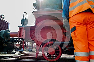 Railway worker in action with steam train in background