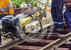 Railway workers bolting track rail. Close up photo