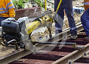 Railway workers bolting track rail. Detail worker with mechanical bolting wrench