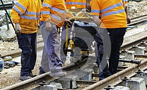 Railway workers bolting track rail. Detail worker with mechanical bolting wrench