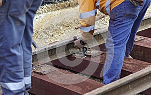 Railway workers bolting track rail. Detail worker with mechanical bolting wrench