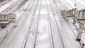 Railways in snow in train station among the stairs, top view, camera move ahead.