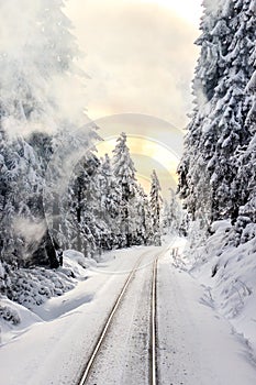 Železnice v zasněžený les na západ slunce 