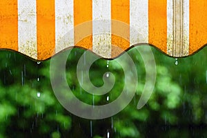 Rain. Awning on a balcony and drops of water on a natural colorful background during a spring day.