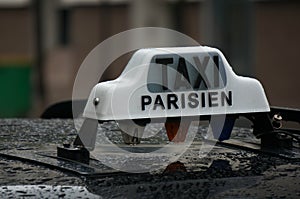 Rain on a black Paris taxi with a white Taxi Parisien sign on top