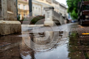 Rain in the city, drops are falling. Close-up of the sidewalk. Urban background and texture. Blurred abstract image