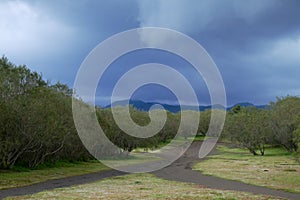 Rain clouds on bifurcation of dirt road in Etna Park