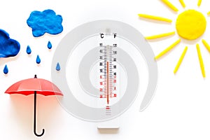 Rain concept. Weather thermometer near umbrella on white background top view copy space