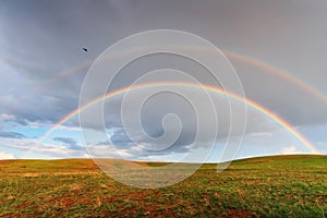 After the rain, a double rainbow over the fields of lush grass in the fields