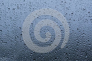 Rain drop on glass window with blue background