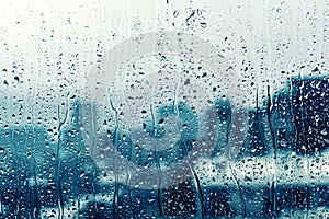 Rain drop on window glass over blurred big city