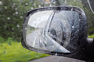 Rain drop on wing mirror or outside mirror of car while driving on road in rainy day. Drive carefully in rainy day