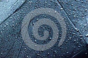 Rain Drops On Black umbrella. Extreme Close-up. Falling Rain drops on parasol. Abstract texture pattern. Rainy Season Nature