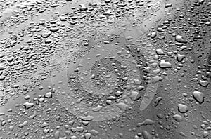 Rain drops on black and white metal surface.