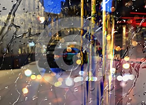 Rain drops on building  windows   rainy evening city street traffic car blurred light at night photo