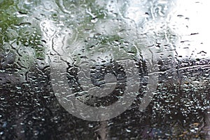 Rain drops on car front window in high contrast, lonely and abstract water background