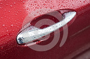 rain drops on chromed handle of red luxury car