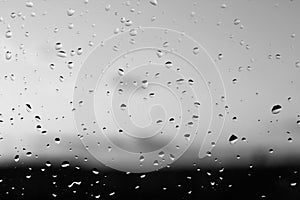 Rain drops and defocused sky background in black and white.