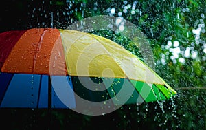 Rain drops falling on rainbow umbrella