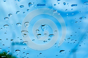 Rain drops on the front window of a car with blurred background of blue sky over traffic road during the rainy season concept