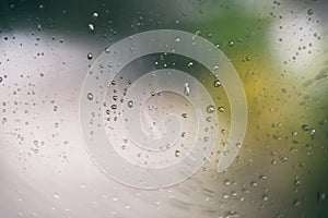 Rain drops on glass - Rainy day window glass with water drops and nature green blur background , selective focus