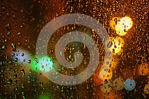 Rain drops on glass surface with bokeh night city lights from lanterns