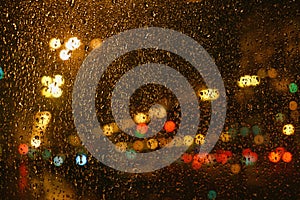 Rain drops on glass surface with bokeh night city lights from lanterns