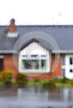 Rain Drops on Glass Window with A House Blurred at Background.