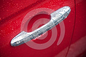 Rain drops on metallic handle on red car