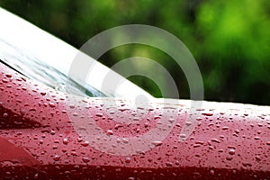 Rain drops on the red car surface, water droplets wet on red car`s surface hood, water rain drop wet on red texture, water stain