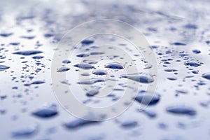 Rain drops on the red car surface. Water srops on car hood. Water drops on blue metal surface.