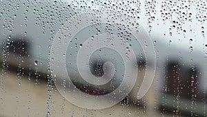 Rain drops on room window glass. Rainy weather in city. Dramatic cityscape.
