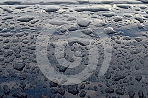 Rain drops on top of the dark car roof